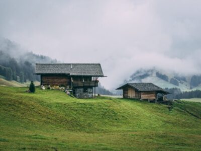 Rural area with wooden houses surrounded by forests with hills covered in the fog on the background